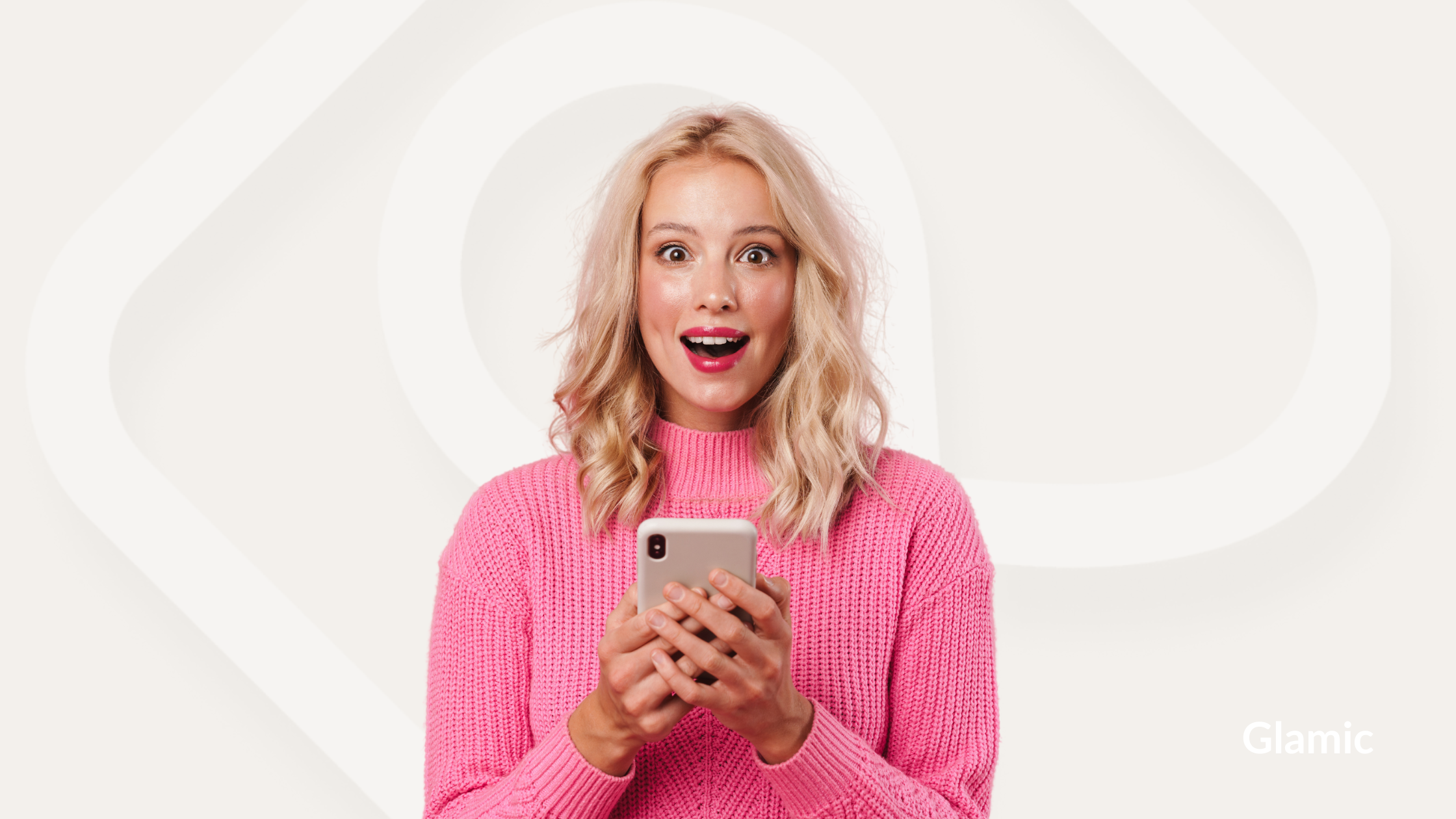Happy blonde woman in pink, holding a phone, surprised by the Glamic app, with a beige background and Glamic logo